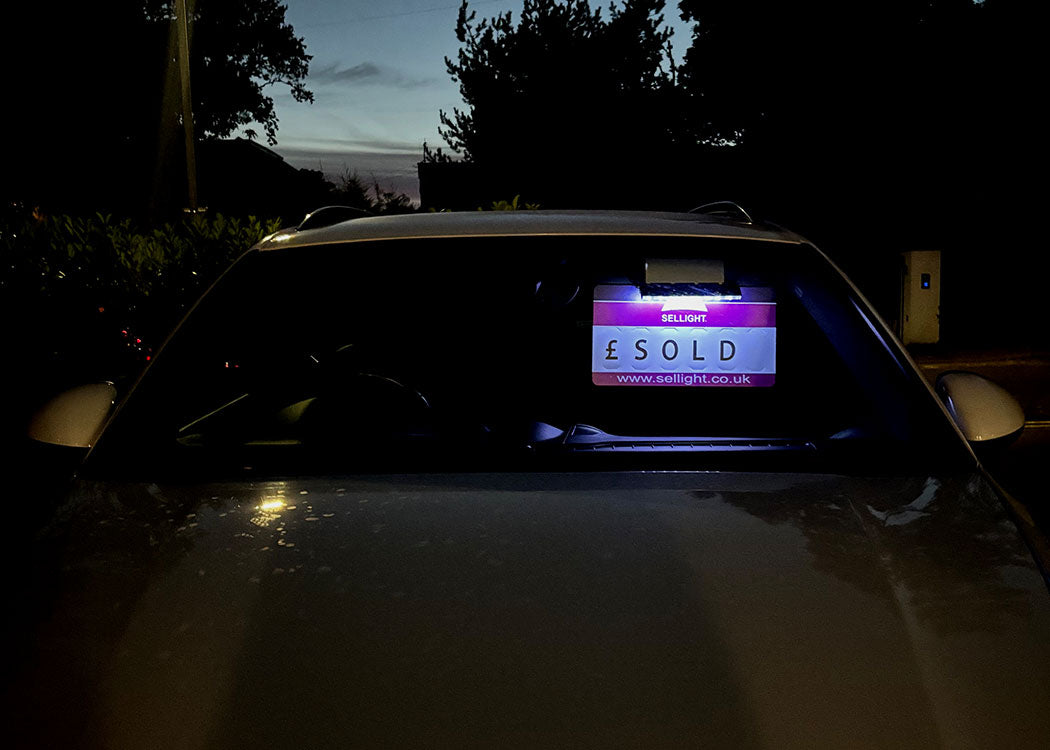 Car with a digital screen displaying 'SOLD' at night